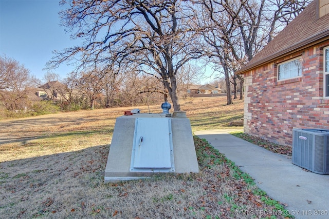 entry to storm shelter featuring central AC and a lawn