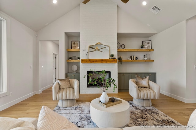 living room with vaulted ceiling, built in features, a fireplace, and light hardwood / wood-style flooring