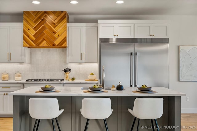 kitchen with stainless steel appliances, white cabinetry, a kitchen island, and light stone counters