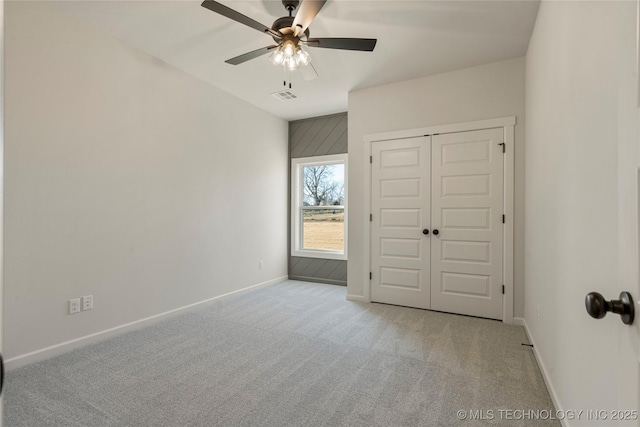 unfurnished bedroom featuring ceiling fan, light carpet, and a closet