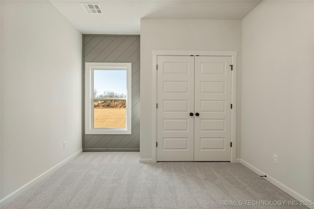 unfurnished bedroom with light colored carpet and a closet