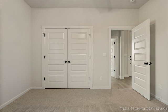 unfurnished bedroom with light colored carpet and a closet