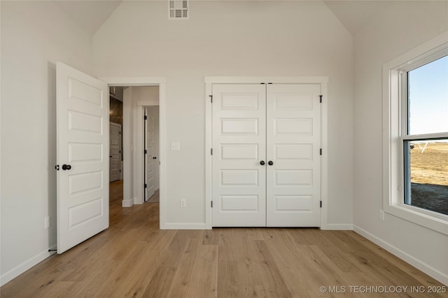 unfurnished bedroom with light hardwood / wood-style floors, multiple windows, and lofted ceiling