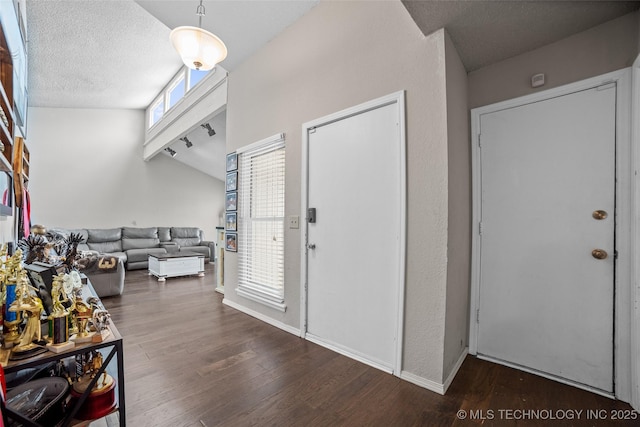 entryway featuring a textured ceiling, dark hardwood / wood-style floors, and vaulted ceiling