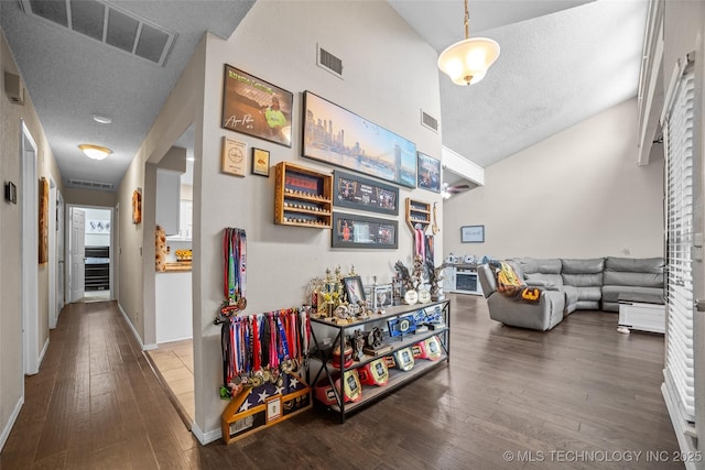 corridor featuring lofted ceiling, a textured ceiling, and hardwood / wood-style flooring