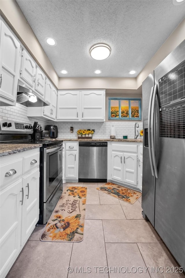 kitchen featuring white cabinetry, stainless steel appliances, backsplash, a textured ceiling, and light tile patterned floors