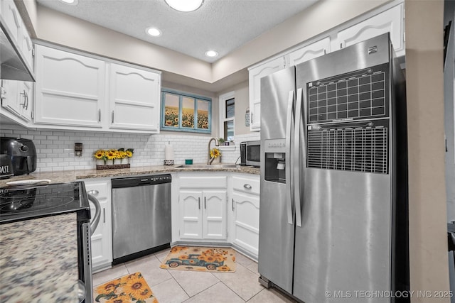 kitchen with stainless steel appliances, white cabinetry, and tasteful backsplash