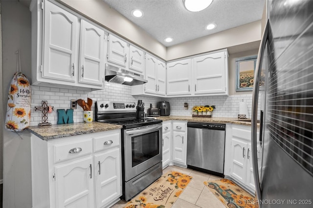 kitchen with white cabinetry, light stone counters, light tile patterned floors, and stainless steel appliances