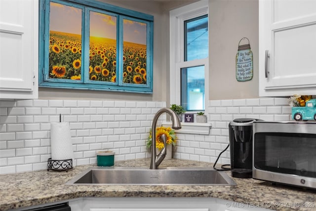 details featuring dishwashing machine, white cabinetry, sink, and light stone countertops