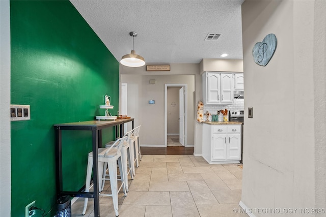 kitchen with tasteful backsplash, light tile patterned flooring, white cabinets, and hanging light fixtures