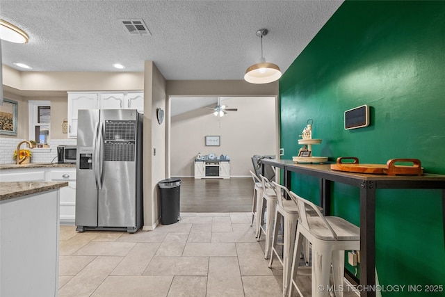 kitchen featuring tasteful backsplash, a textured ceiling, stainless steel appliances, ceiling fan, and white cabinets