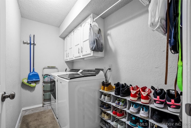 laundry area featuring washer and clothes dryer, cabinets, and a textured ceiling