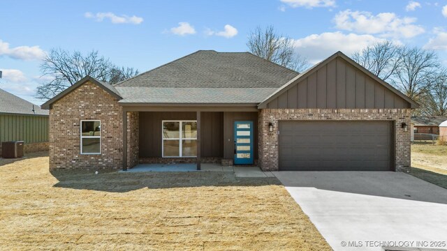 404 W 7th St, Dewey, OK 74029 - view of front of property featuring central AC unit, an attached garage, brick siding, concrete driveway, and board and batten siding
