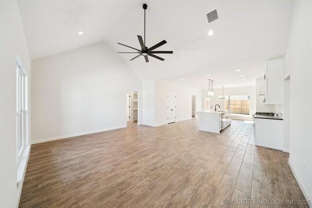 404 W 7th St, Dewey, OK 74029 - unfurnished living room featuring visible vents, light wood finished floors, high vaulted ceiling, ceiling fan, and a sink