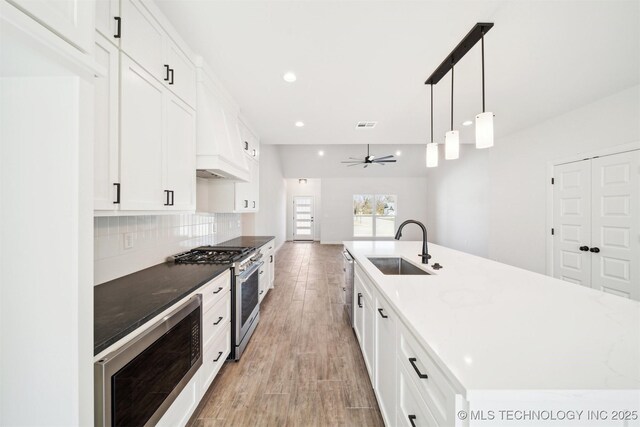 404 W 7th St, Dewey, OK 74029 - kitchen with a large island, a sink, backsplash, white cabinetry, and appliances with stainless steel finishes