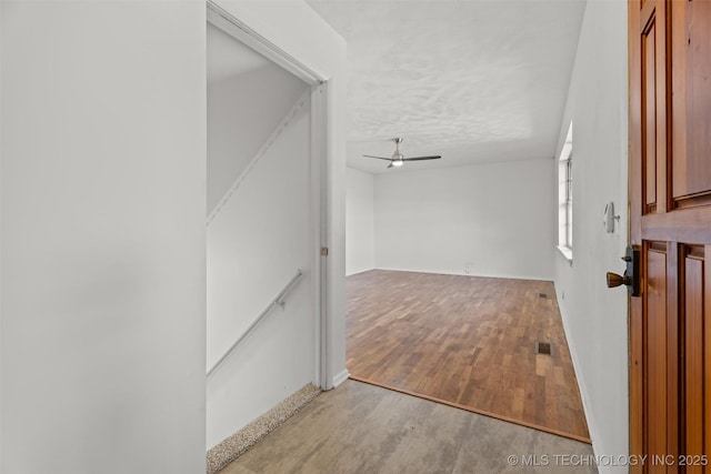 hallway with a textured ceiling and light hardwood / wood-style flooring