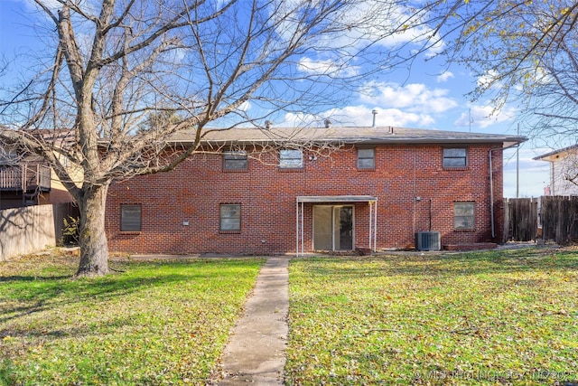 back of house featuring a yard, brick siding, fence, and central AC unit