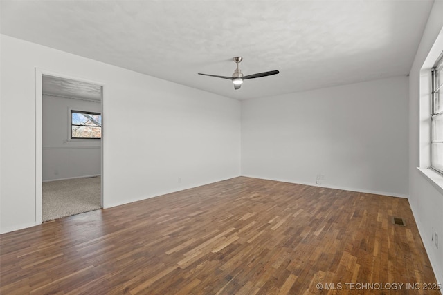 empty room with ceiling fan and dark wood-type flooring