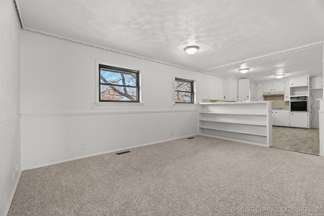 interior space featuring light colored carpet and a textured ceiling