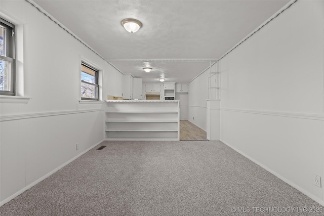 basement featuring light carpet and a textured ceiling