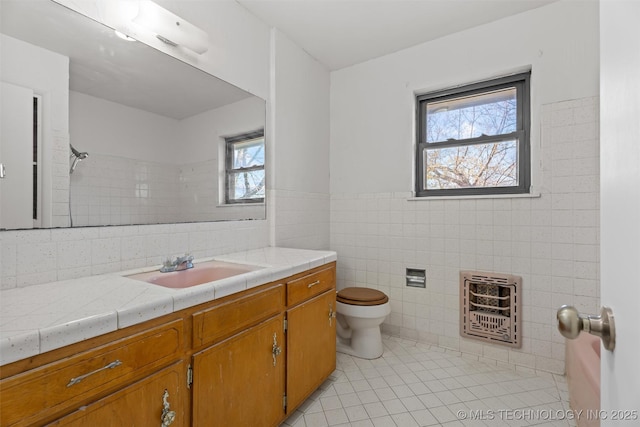 bathroom with tile patterned floors, vanity, heating unit, tile walls, and plenty of natural light