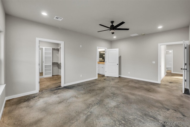 unfurnished bedroom featuring concrete floors, a closet, a spacious closet, and ceiling fan