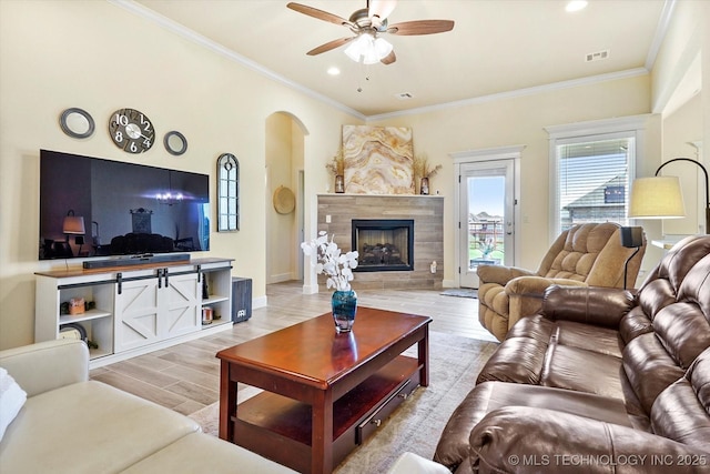 living room with a premium fireplace, ceiling fan, light hardwood / wood-style flooring, and crown molding