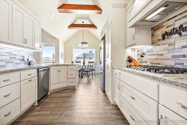 kitchen featuring stainless steel appliances, lofted ceiling with beams, premium range hood, decorative backsplash, and white cabinets