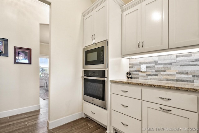 kitchen featuring stainless steel oven, light stone countertops, built in microwave, tasteful backsplash, and white cabinetry