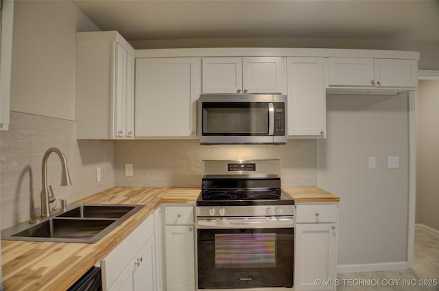 kitchen with butcher block counters, sink, white cabinets, and stainless steel appliances