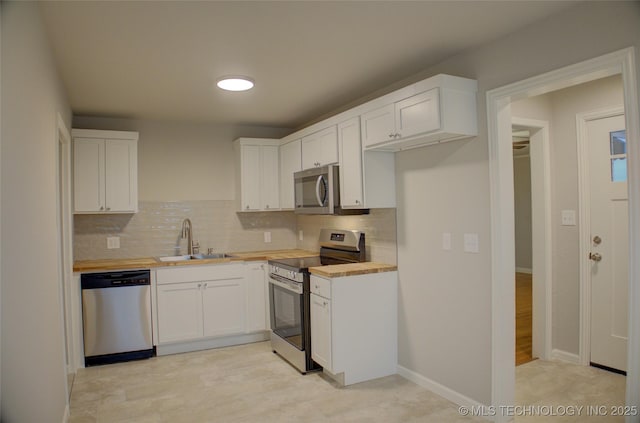 kitchen with wood counters, sink, white cabinetry, and stainless steel appliances