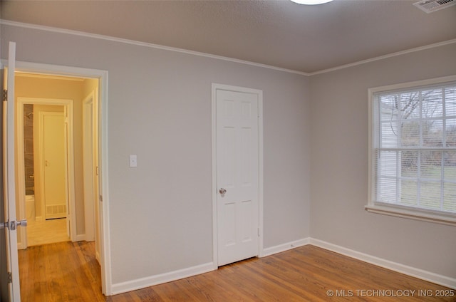 empty room featuring plenty of natural light, ornamental molding, and hardwood / wood-style flooring