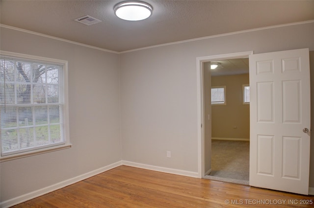 unfurnished room featuring light hardwood / wood-style floors, a textured ceiling, and ornamental molding