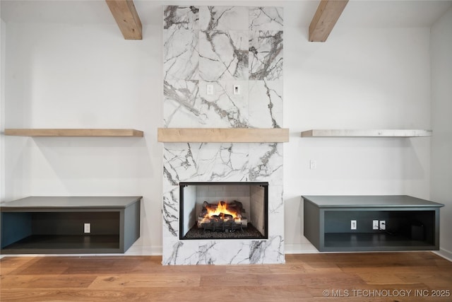 details with beamed ceiling, hardwood / wood-style flooring, and a fireplace