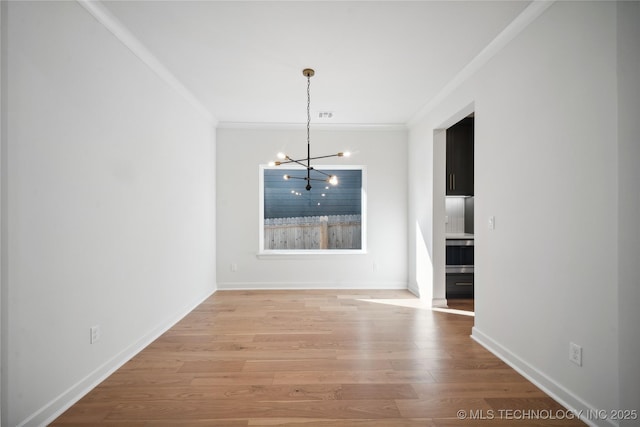 unfurnished dining area with an inviting chandelier, light wood-type flooring, and ornamental molding