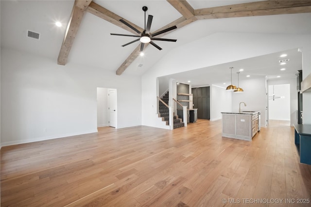 unfurnished living room with ceiling fan, beam ceiling, light hardwood / wood-style floors, and high vaulted ceiling