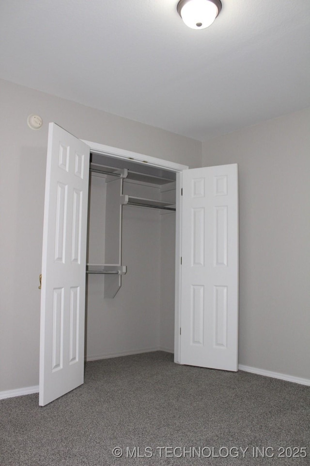 unfurnished bedroom with dark carpet and a closet