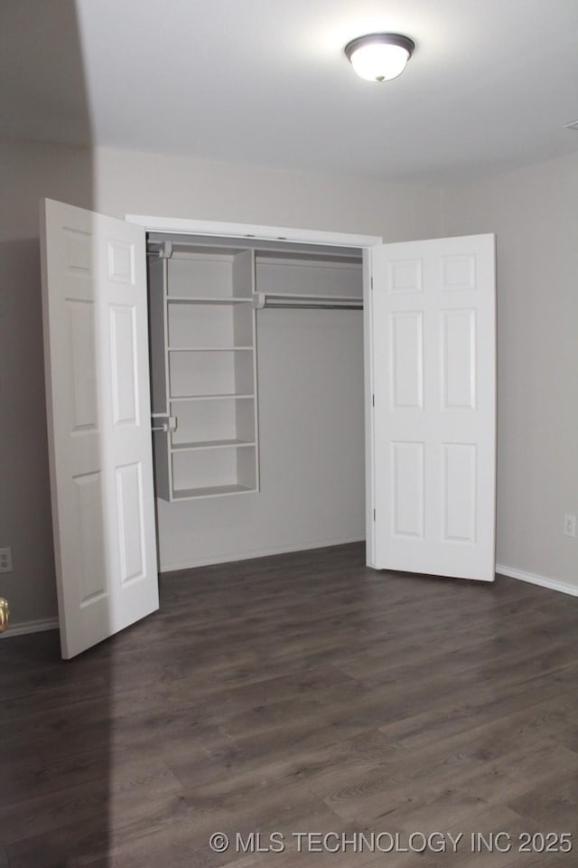 unfurnished bedroom with a closet and dark wood-type flooring