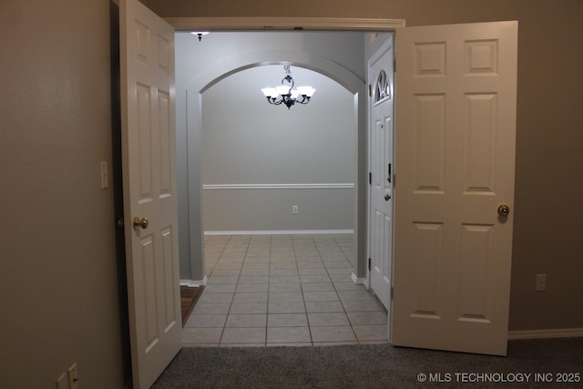 hallway with light tile patterned floors and an inviting chandelier