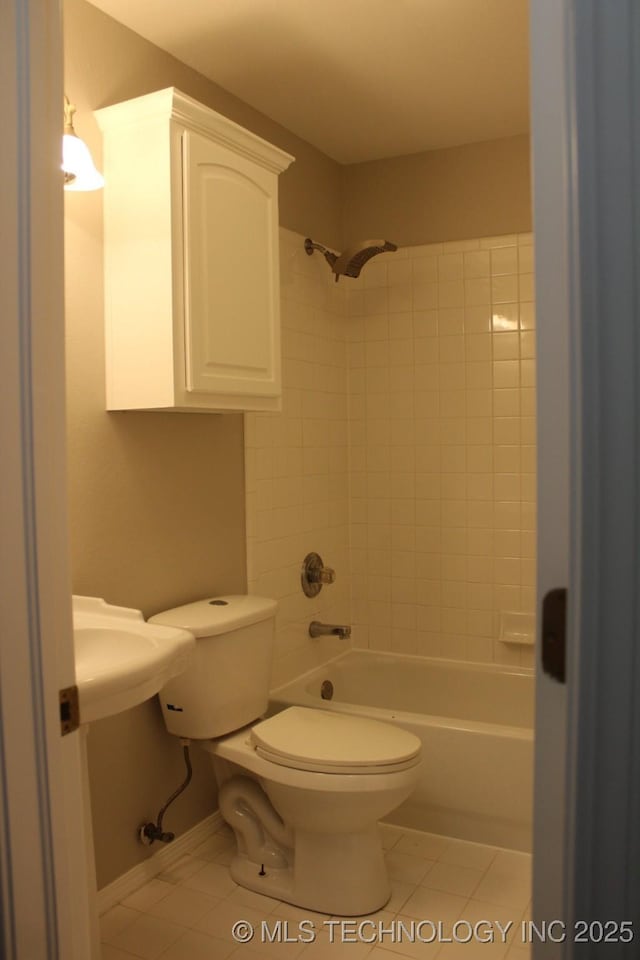 bathroom with tile patterned flooring, toilet, and tiled shower / bath