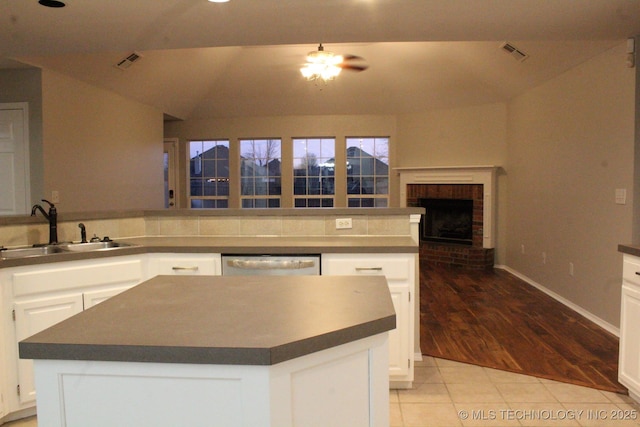 kitchen with white cabinets, a center island, light tile patterned flooring, and sink