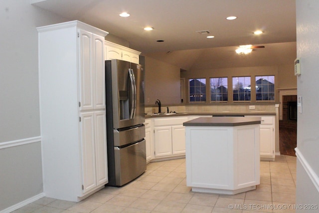 kitchen featuring vaulted ceiling, sink, light tile patterned floors, white cabinets, and stainless steel fridge with ice dispenser