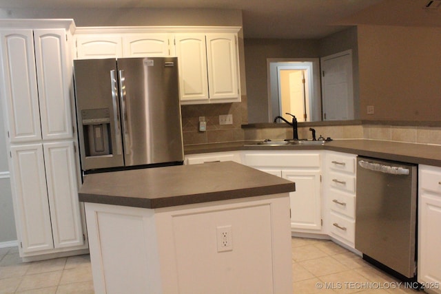 kitchen featuring white cabinets, sink, light tile patterned floors, appliances with stainless steel finishes, and a kitchen island