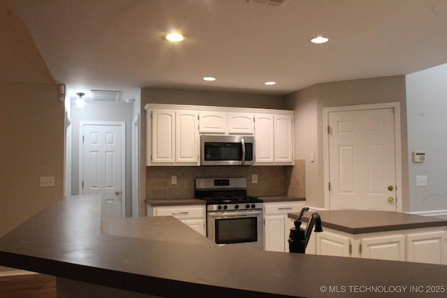 kitchen featuring decorative backsplash, white cabinetry, dark hardwood / wood-style flooring, and appliances with stainless steel finishes