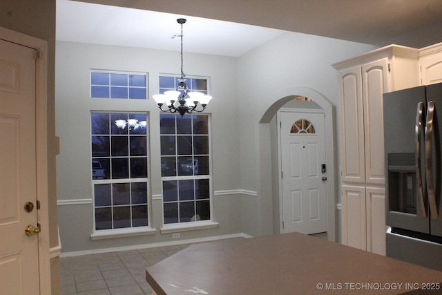 unfurnished dining area with light tile patterned flooring and an inviting chandelier