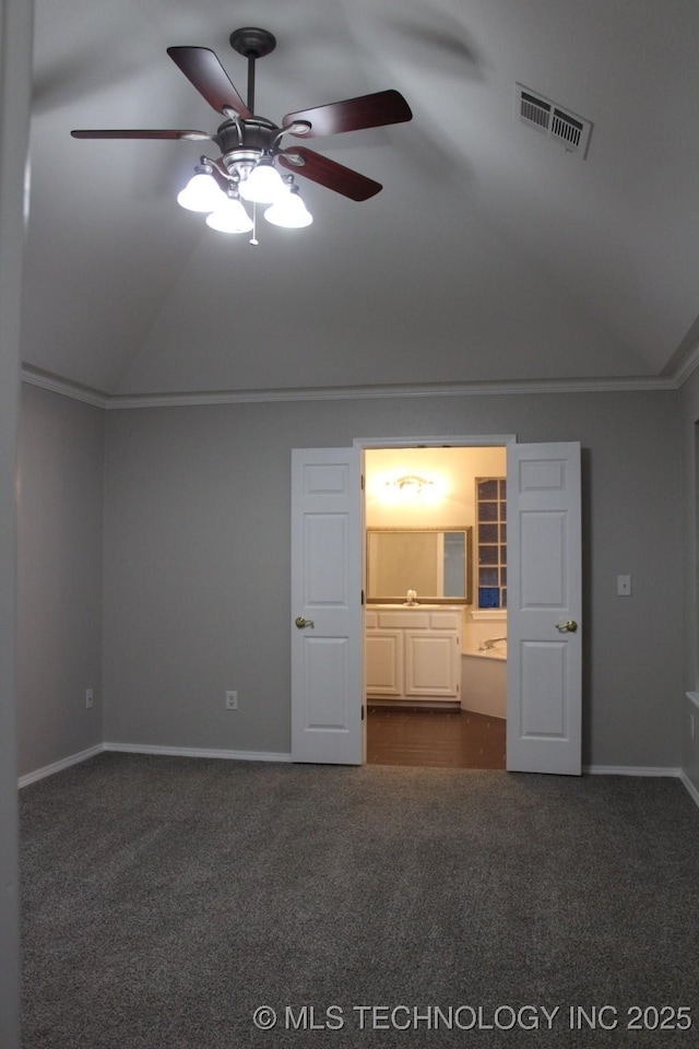 interior space featuring ensuite bath, ceiling fan, lofted ceiling, and dark colored carpet