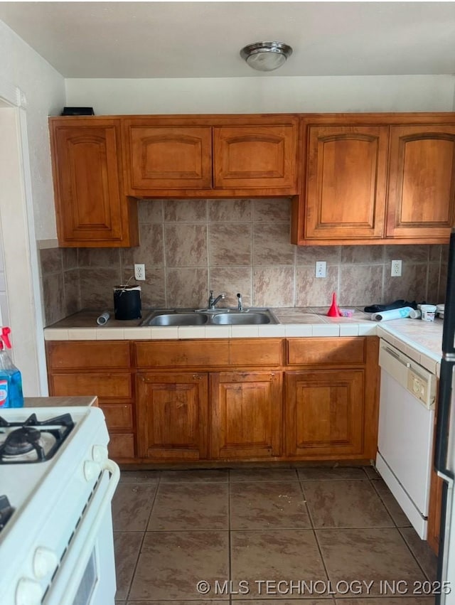 kitchen with tile countertops, white appliances, sink, dark tile patterned floors, and tasteful backsplash