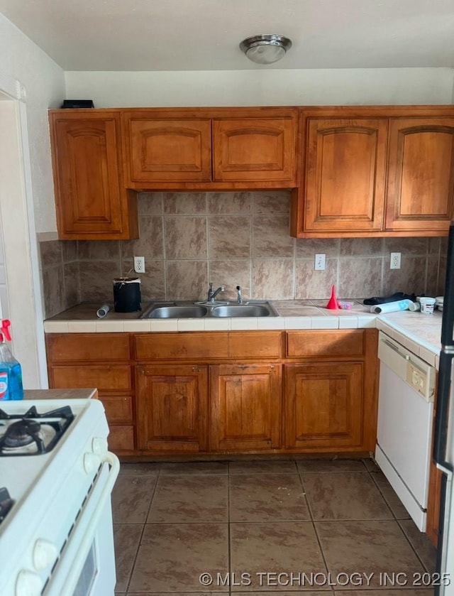 kitchen featuring tasteful backsplash, white appliances, sink, tile countertops, and dark tile patterned flooring