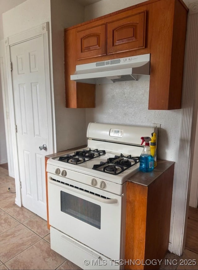 kitchen with light tile patterned flooring and white range with gas stovetop