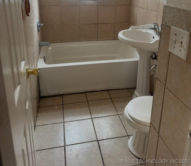 bathroom with tile patterned flooring, tub / shower combination, and toilet